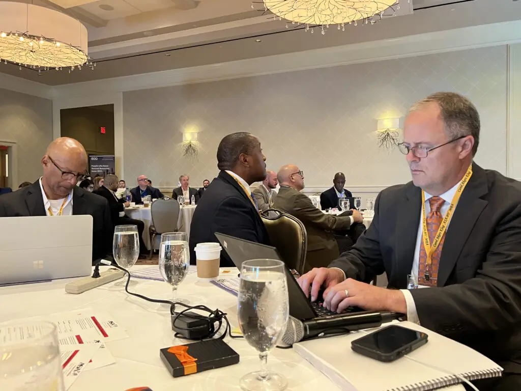 A group of people sitting at tables with laptops.