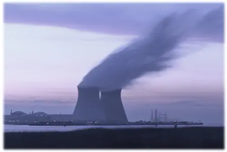 A large cooling tower with smoke coming out of it.